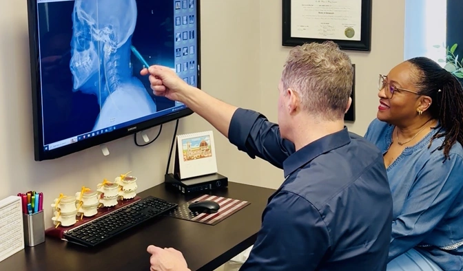 James Roeder pointing to a patient's X-ray on a computer monitor while the patient looks on.
