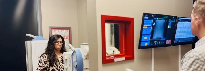 James Roeder assisting a patient during a sciatica diagnostic scan beside a digital imaging machine.
