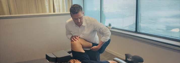 James Roeder supporting a patient's bent leg during a chiropractic examination.
